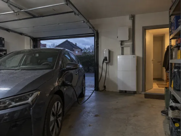 Elektrische wagen aan de laadpaal in de garage, naast de thuisbatterij