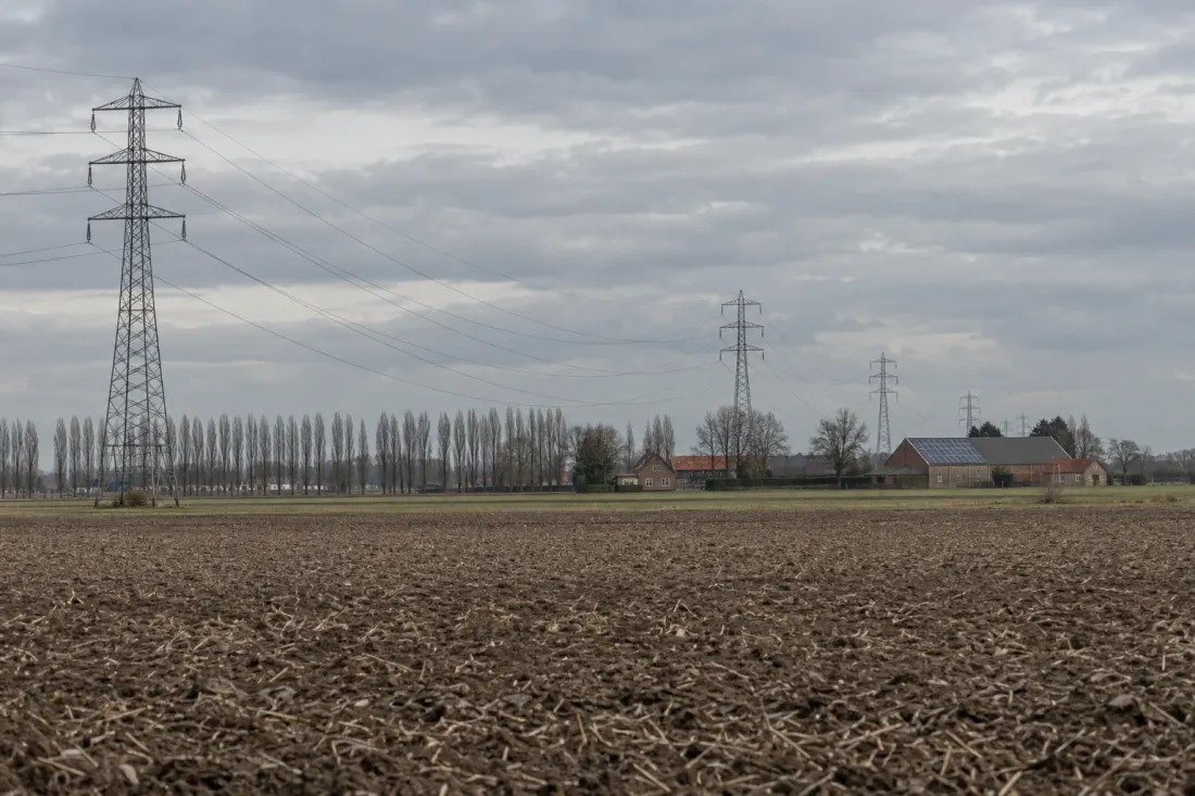Hoogspanningsmasten boven een omgeploegde akker