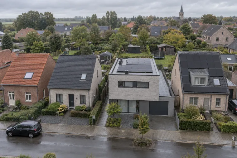 Woonstraat van bovenaf met verschillende daken: rode pannen, donkere pannen, een plat dak en zonnepanelen rond een dakkapel