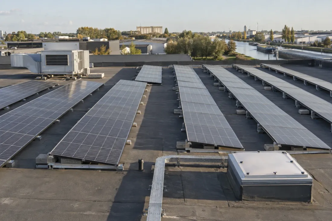 Rijen zonnepanelen in oost-westopstelling op het platte dak van een bedrijfsgebouw