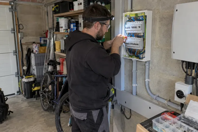 Elektricien sluit een thuisbatterij aan in de zekeringkast in een garage