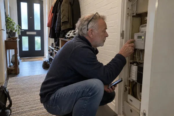 Man leest de digitale elektriciteitsmeter af in de meterkast in de gang