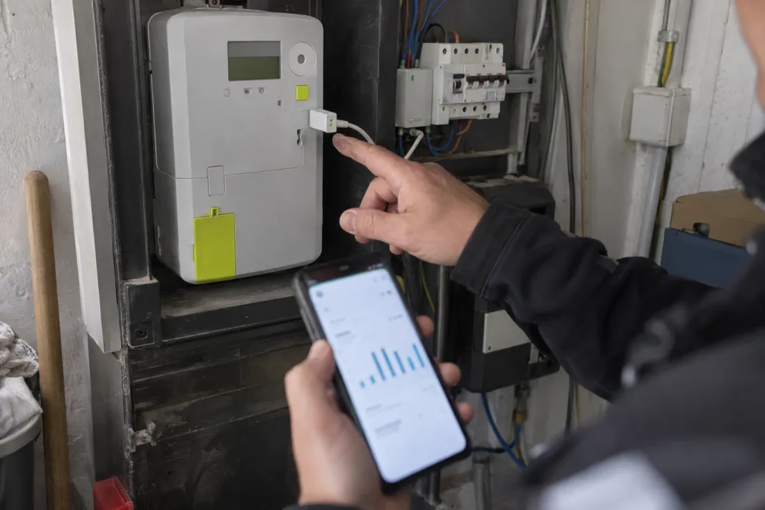 Technicus toont de energie-app naast de digitale meter met een dongle in de gebruikerspoort
